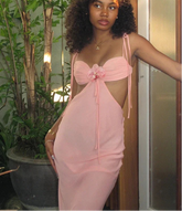 Woman wearing a pink dress standing in front of plants